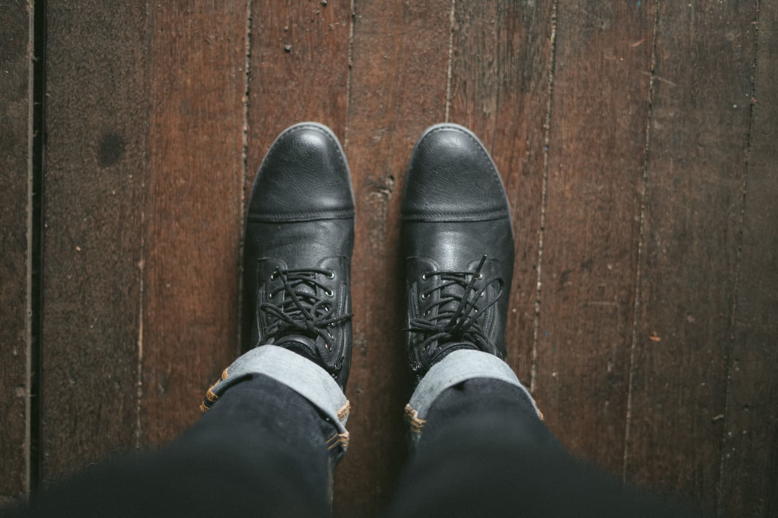 A pair of dark leather boots viewed from above on a wooden floor