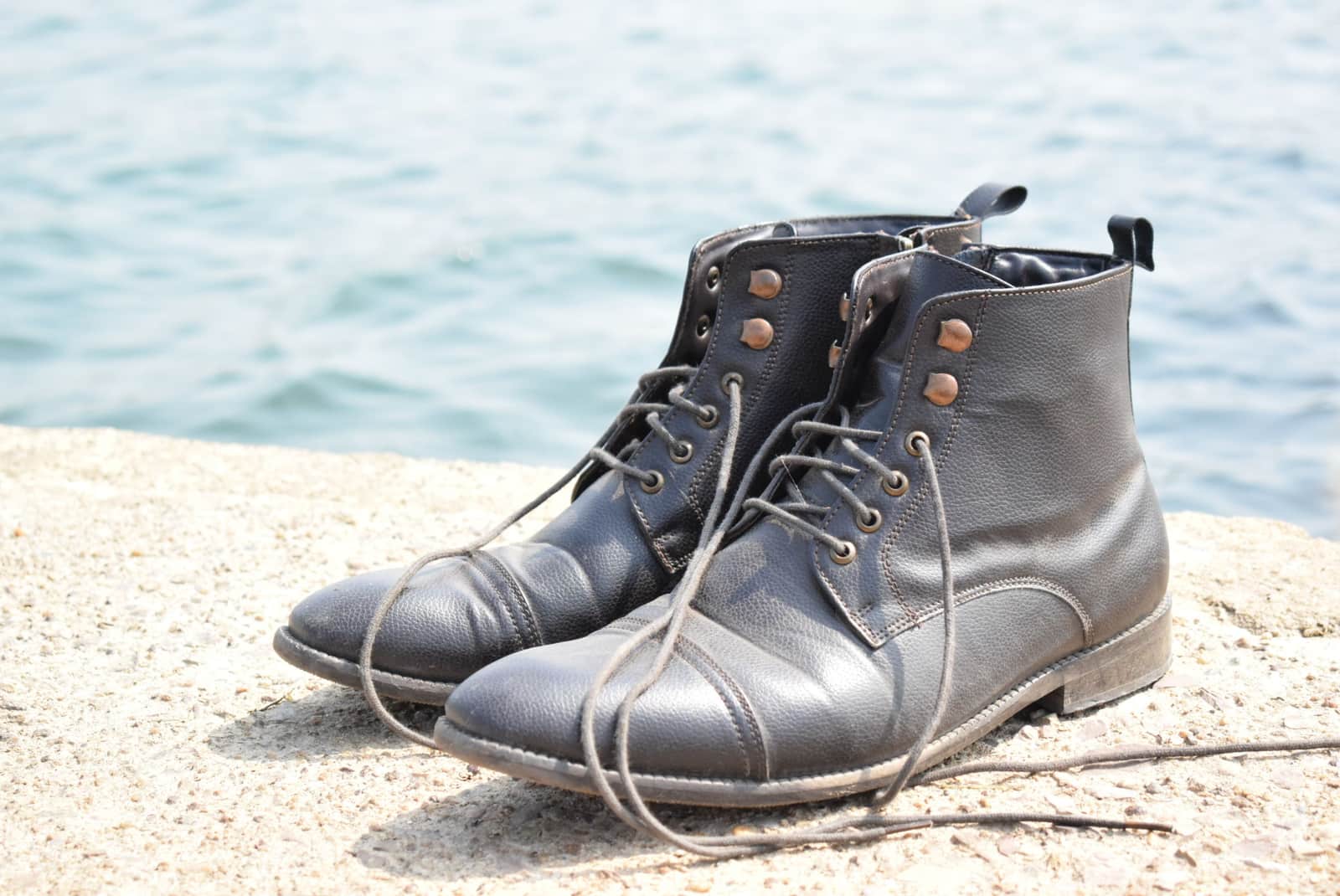 A pair of black leather boots with laces, photographed outdoors