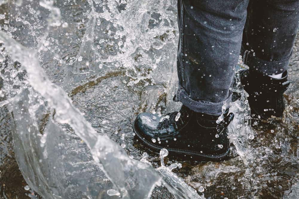 Waterproof rubber boots splashing through a puddle
