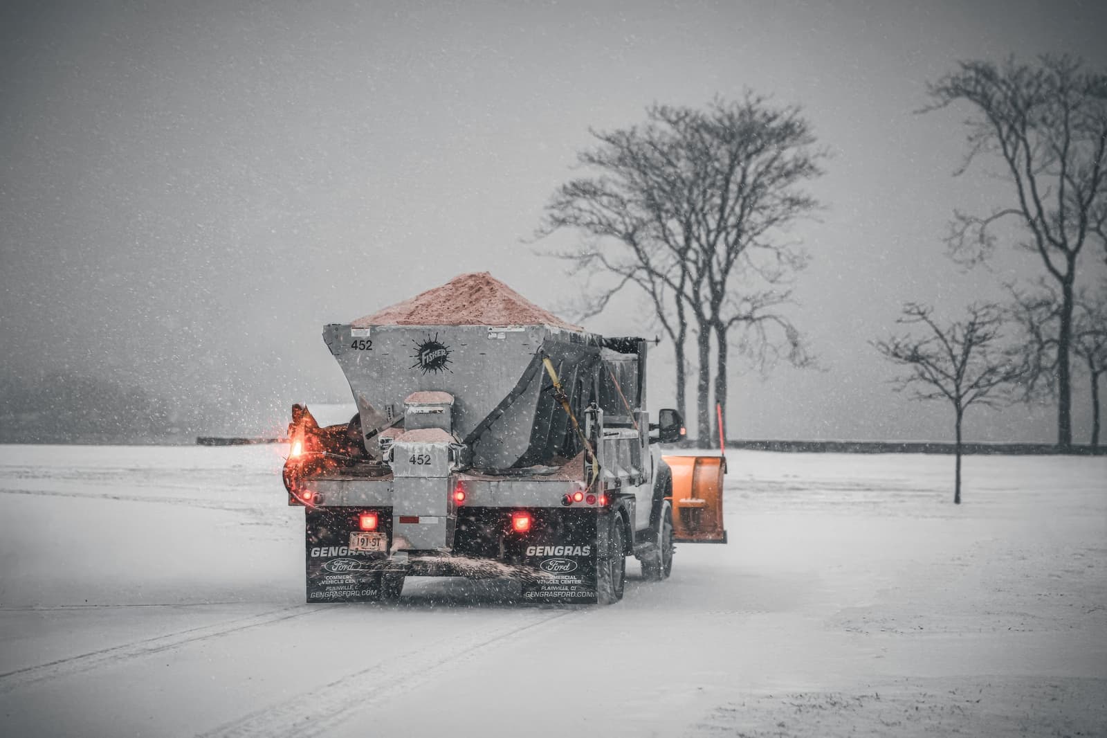 A truck spreading salt across a snow-covered road