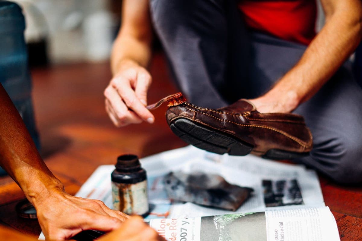 A brown leather boot being buffed with a cloth and brush